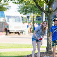 People playing cornhole on Kirkhof Lawn with food truck in the background.